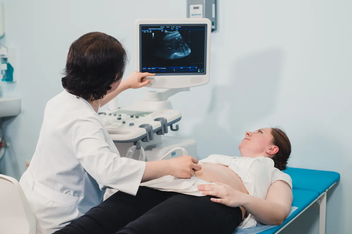 Doctor performing an abdominal ultrasound scan on a patient lying on an exam table
