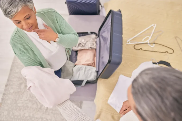 Woman folding clothes beside an open suitcase at home